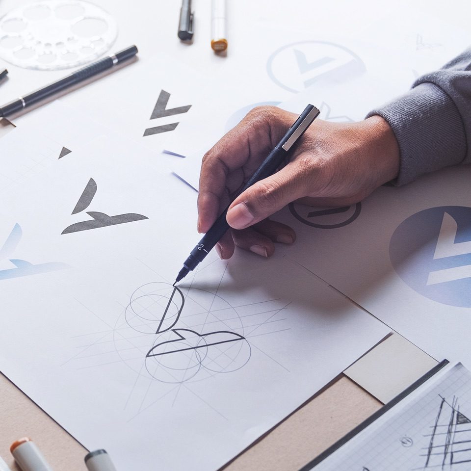 Person drawing shapes on a paper with a black pen