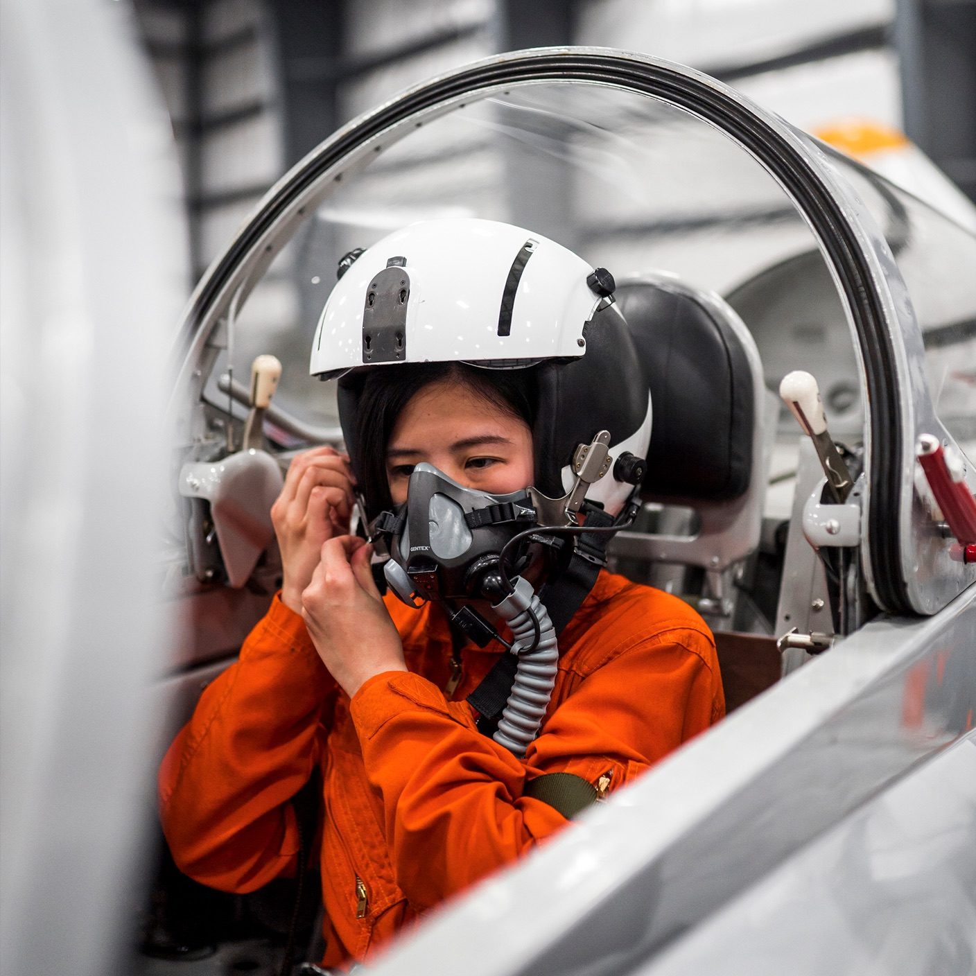 pilot in an orange suit putting on her helmet getting ready for takeoff